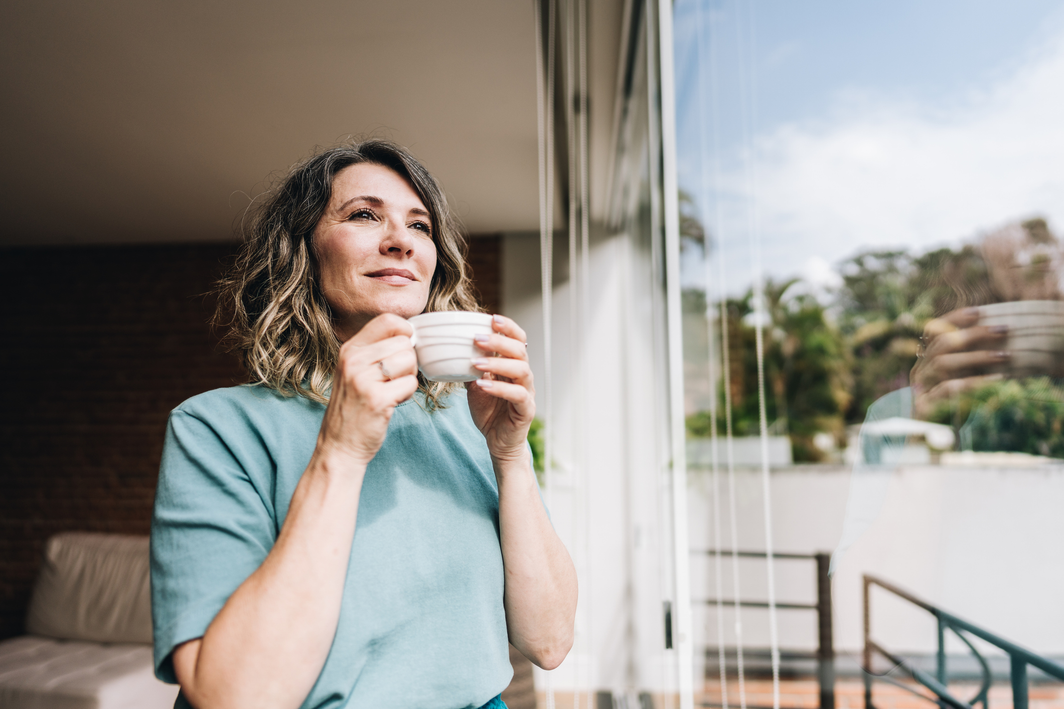 Contemplative mature woman looking throught the window at home relatietherapie | individuele therapie | counseling voor werknemers. Lilian van de Weerdhof | praktijk Alkmaar en online
